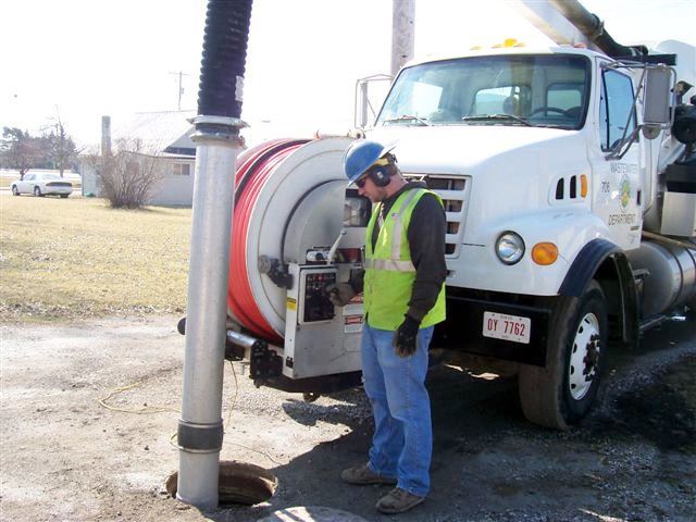 Person Standing Next to Pipe In Hole
